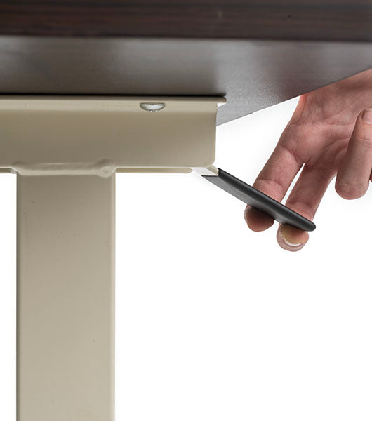 Hand operating black height adjustment lever mechanism underneath dark tabletop surface