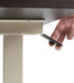 Hand operating black height adjustment lever mechanism underneath dark tabletop surface