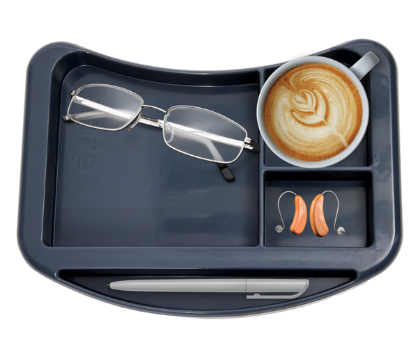 A close-up, top-down view of the organizer tray for an Icare over-bed table. The tray has four compartments: a large one holding a pair of eyeglasses, a medium one holding a cup of latte, a smaller one containing a pair of hearing aids, and a long groove at the bottom of the tray.